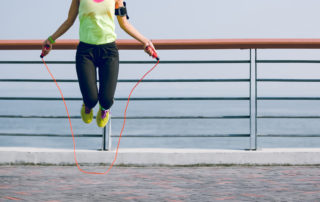 Young fitness woman jumping rope at seaside