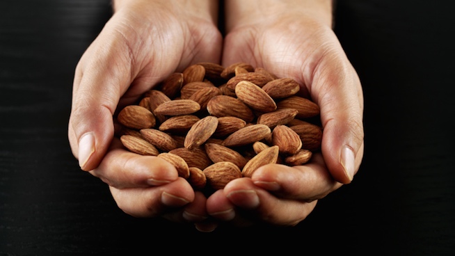 person holding out both hands full of almonds