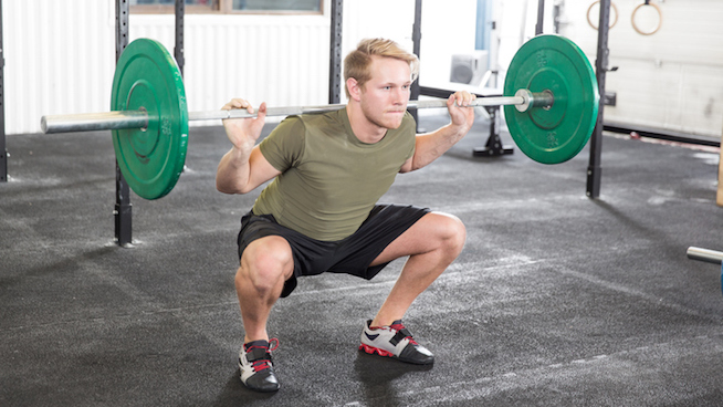 athletic male performing squat at the gym