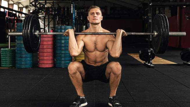 athletic male performing a front squat at gym