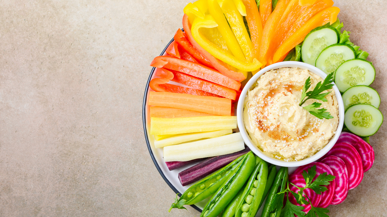 Hummus platter with assorted vegetable snacks. Healthy vegan and vegetarian food. Top view, flat lay, copy space.