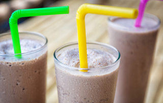 3 glasses with chocolate milkshake with colored straws