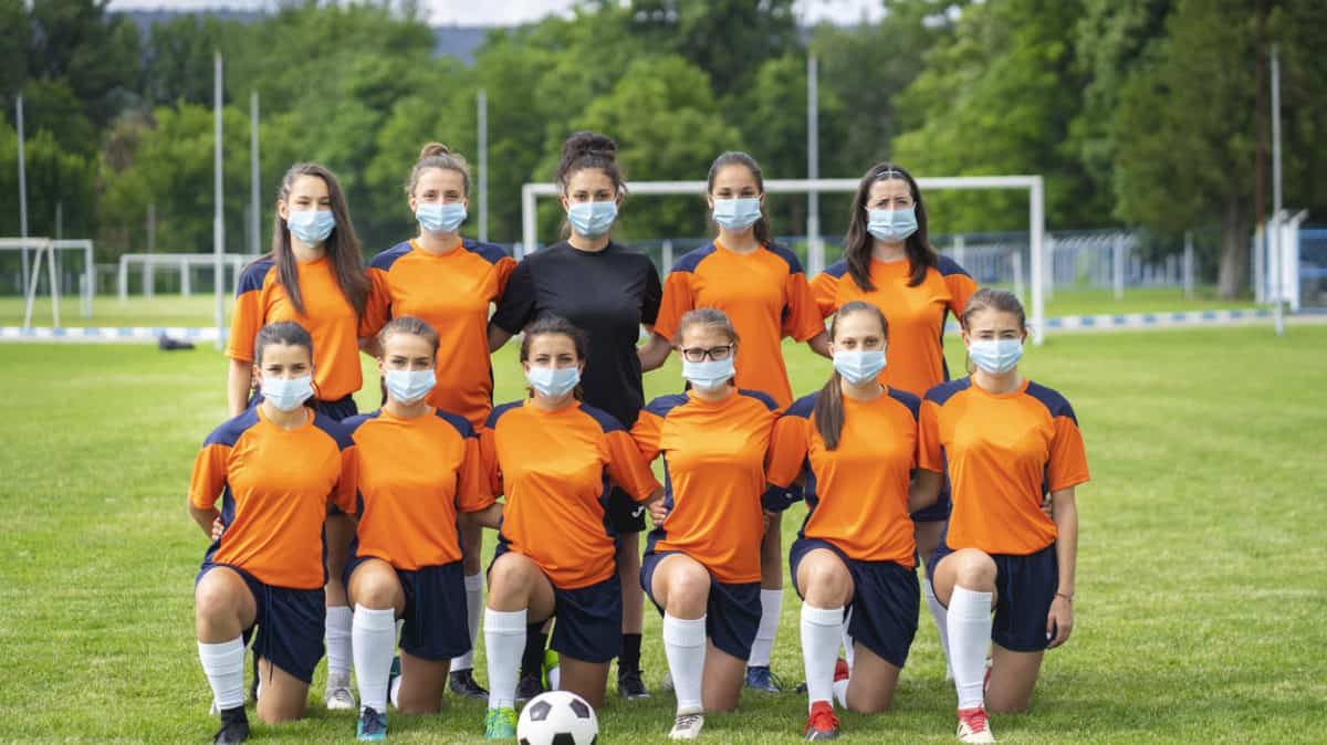 Female soccer team wearing face masks during coronavirus pandemic.