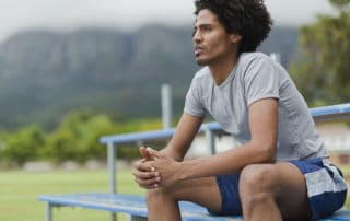 male athlete sitting on bleacher in deep thought